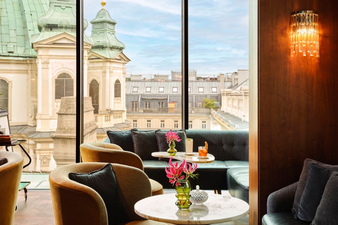 A rooftop restaurant in Vienna with a view of historic buildings through large windows.